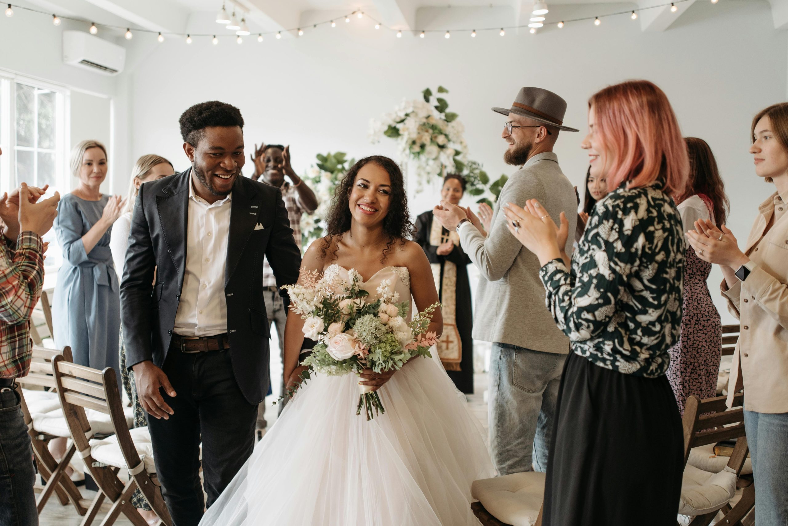 Wedding Shuttle Family Guests NYC: Best Options and Practical Tips for 2026 8 A joyful couple exits the ceremony as guests applaud during their wedding indoors.