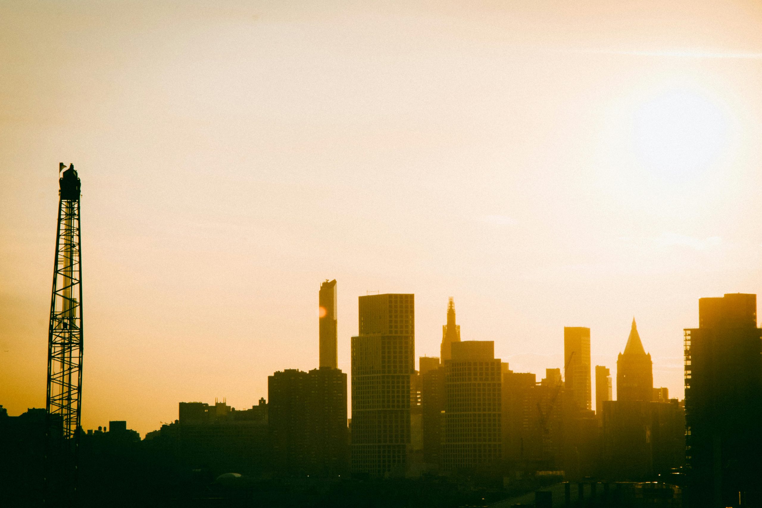 Construction Site Shuttle NYC: Epic 24/7 Amazing Crew Rides! 2 Silhouette of the New York City skyline at sunrise, showcasing a warm and golden urban landscape.