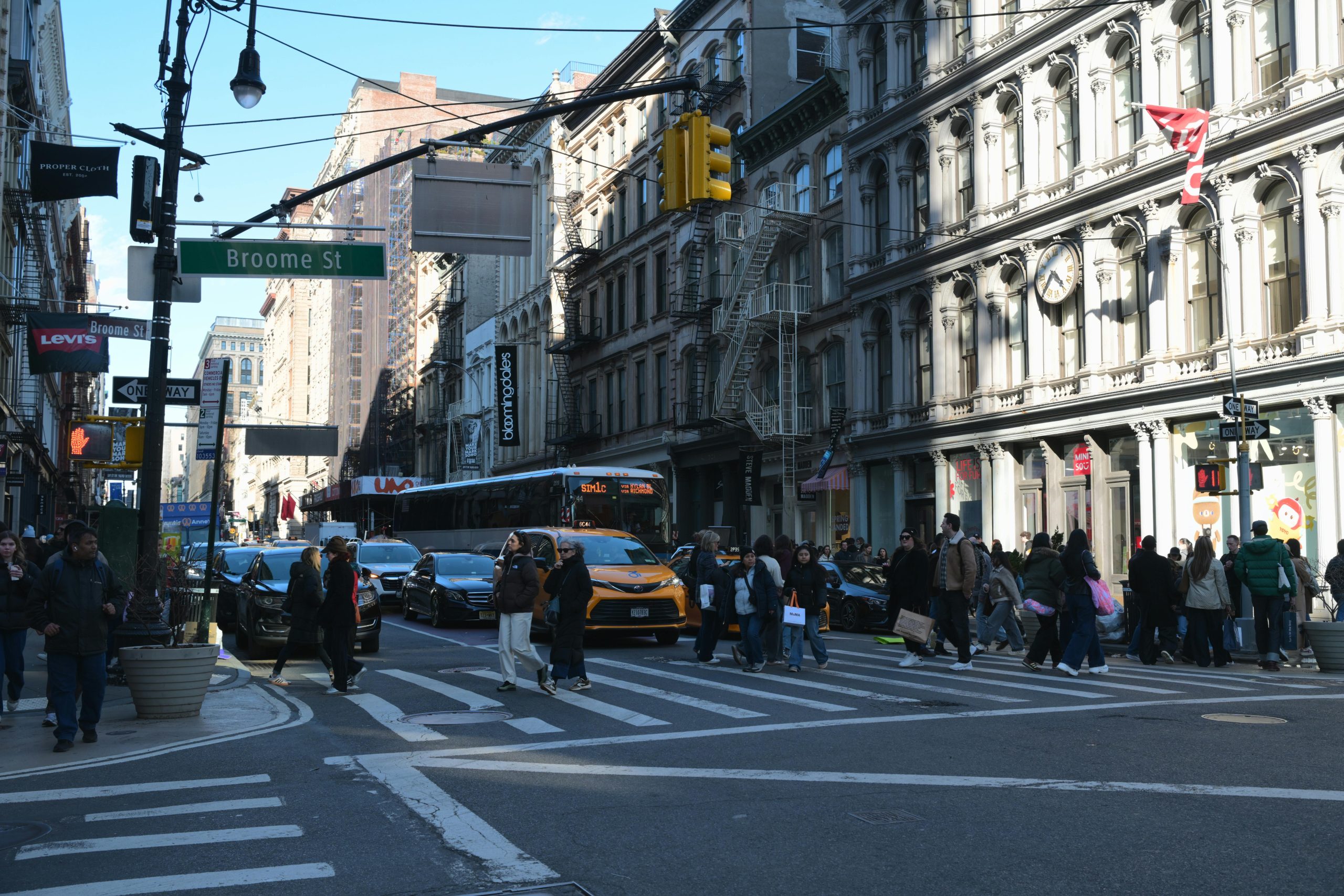 Crowded intersection on Broome Street in bustling SoHo, NYC, during the day.