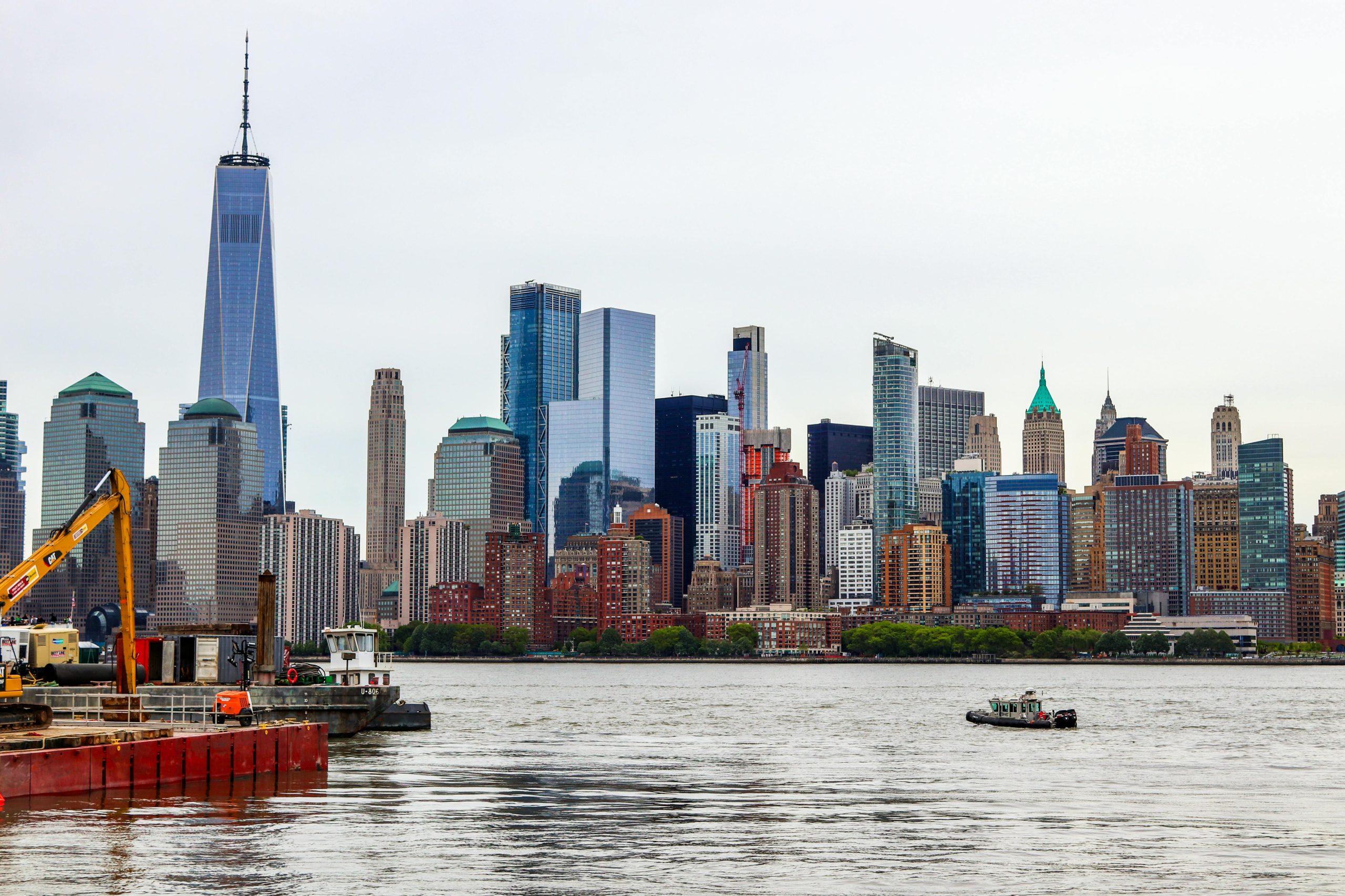 Construction Site Shuttle NYC: 6 Honest Booking Facts for 2026 2 Dramatic view of New York City's skyline with boat on reflective water, overcast sky.