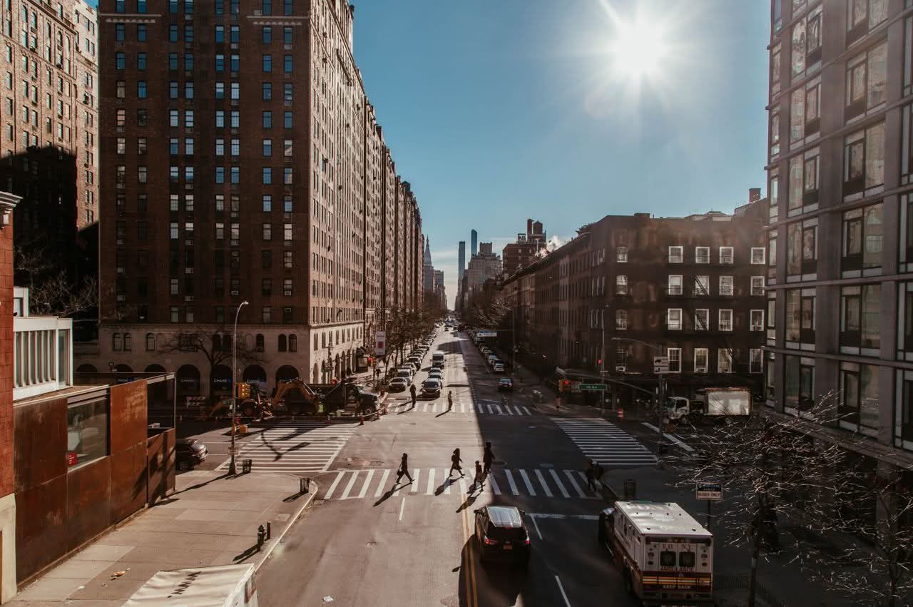 Busy New York City street scene featuring skyscrapers, traffic, and pedestrians in daylight.