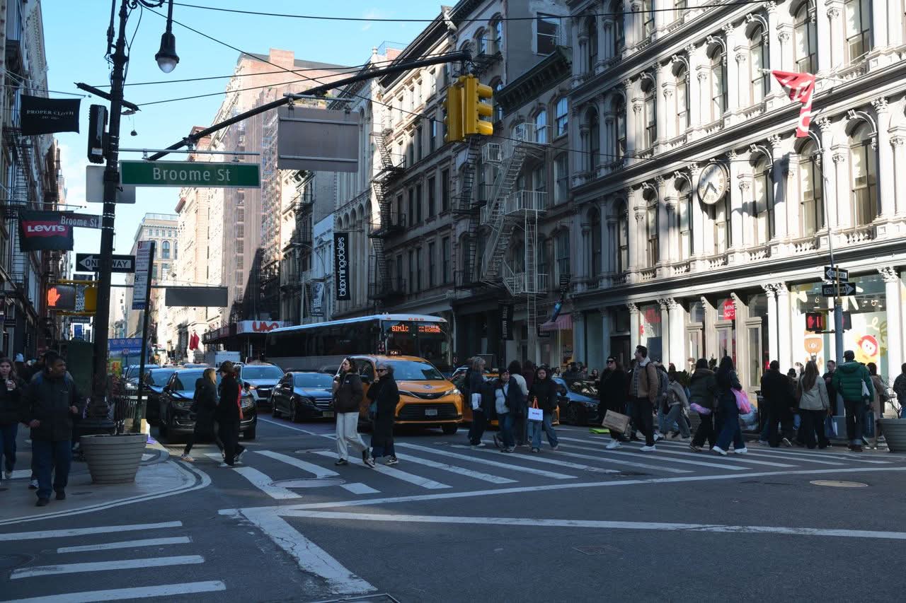 Crowded intersection on Broome Street in bustling SoHo, NYC, during the day.